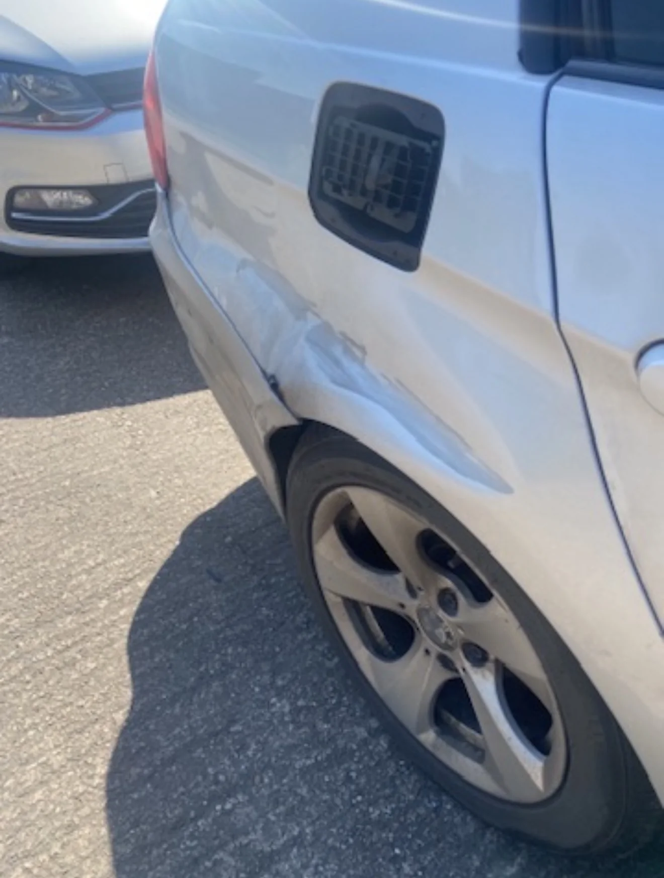 Damaged silver BMW rear quarter panel before repair
